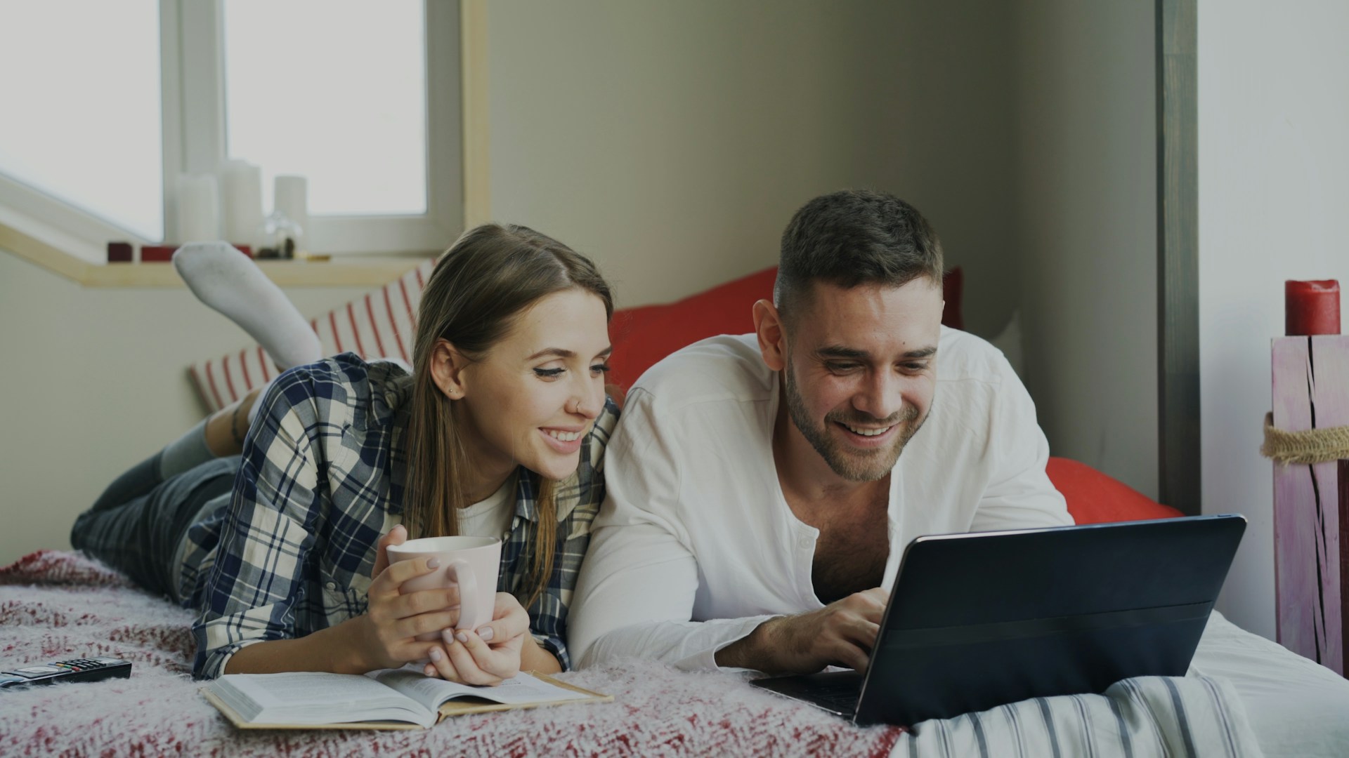 Couple looking at a laptop on a bed