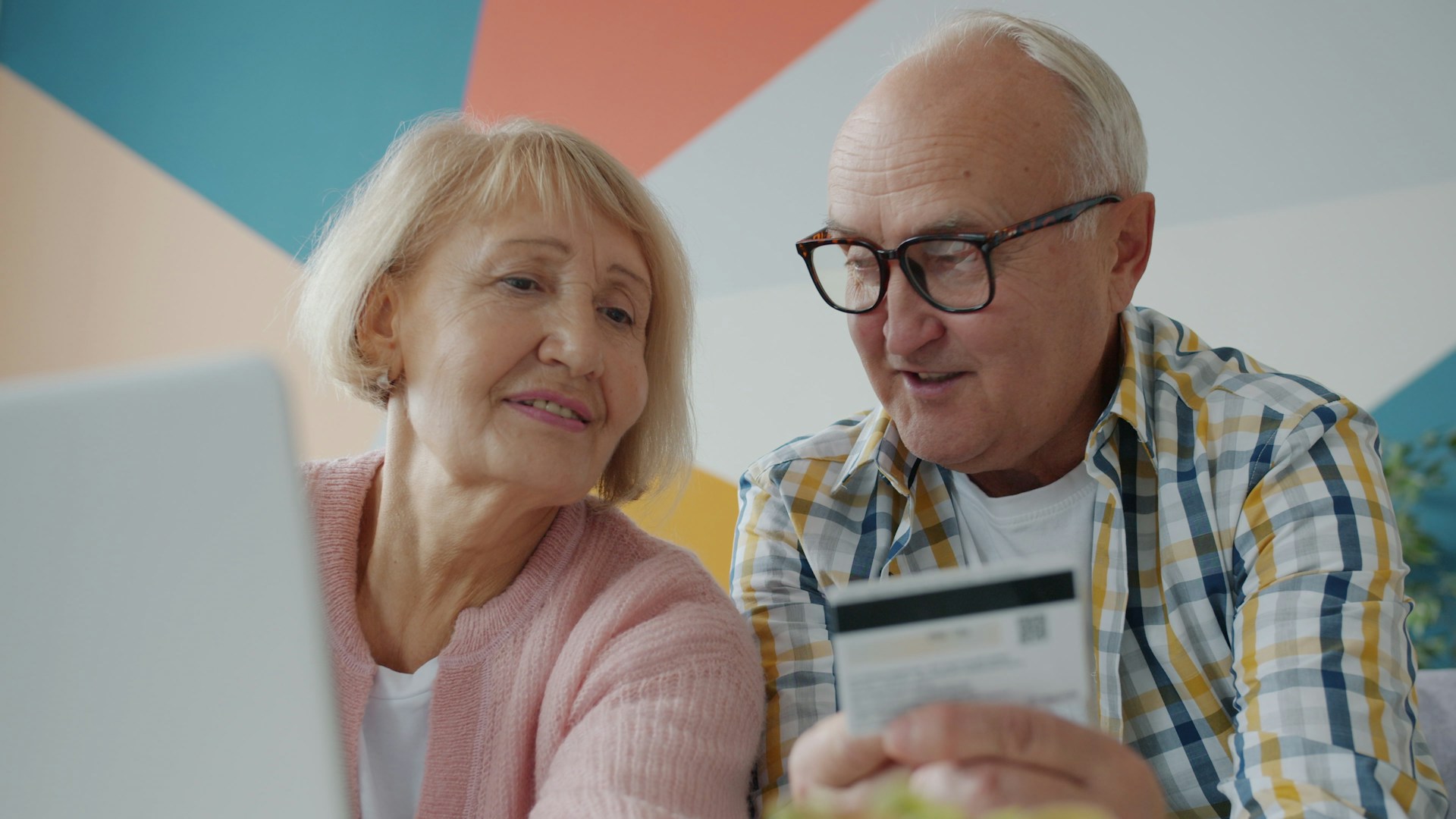 Elderly couple looking at laptop with credit card